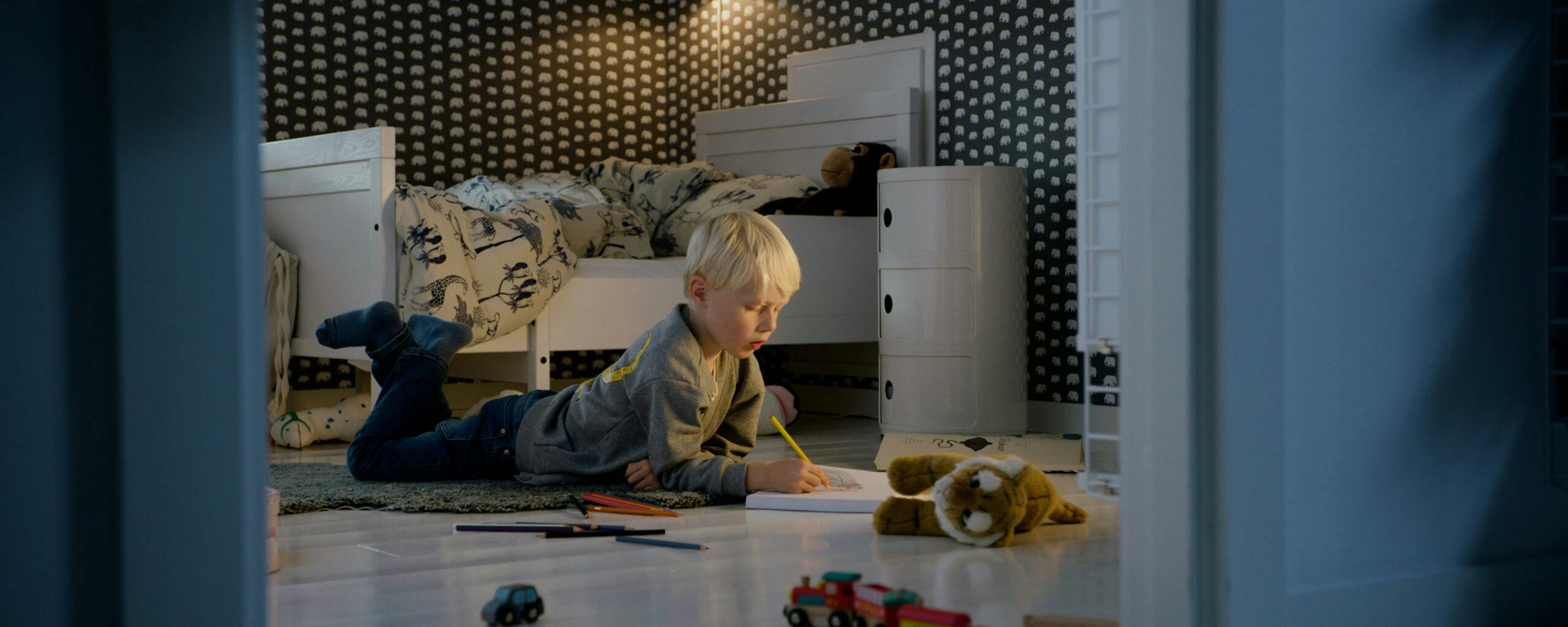 Målande pojke ligger på golvet i filmen "Pojken" för Nõberu of Sweden
