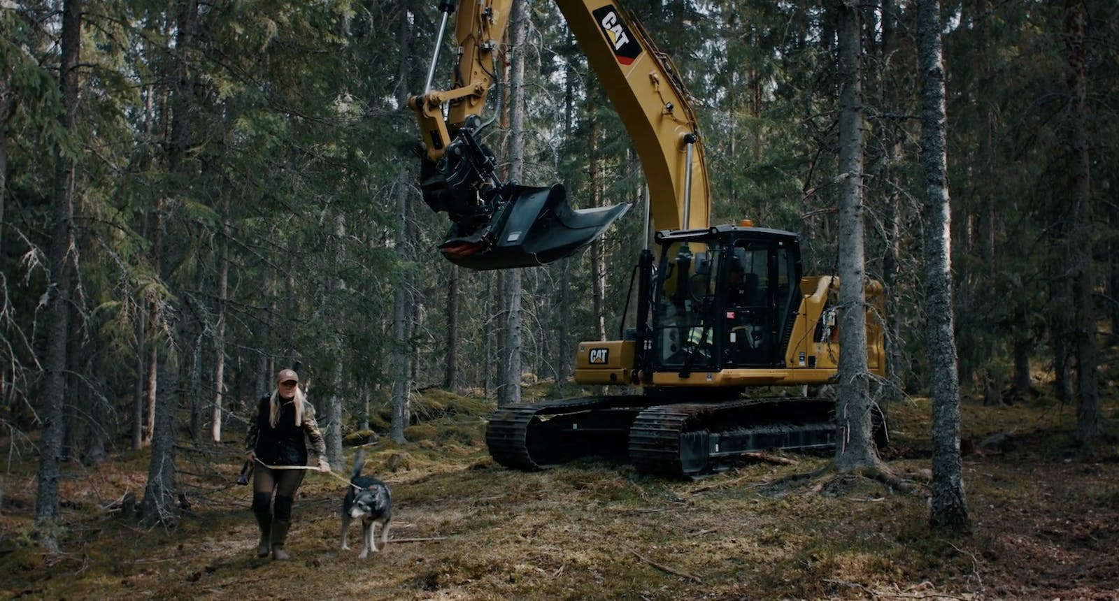 Jägare går i skogen med en grävmaskin hack i häl